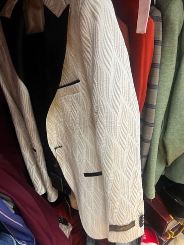Elegant cream jacket with black lapel hanging on a rack.