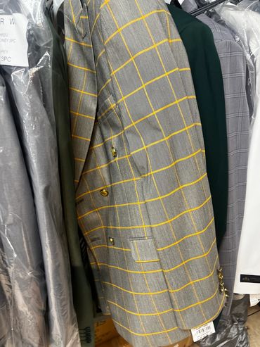 Gray blazer with yellow grid lines hanging among other suits.