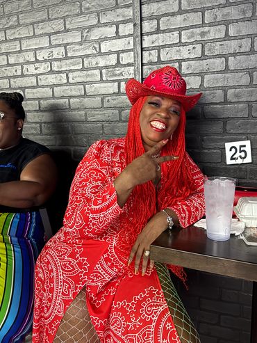 Woman in vibrant red outfit posing happily at a table.