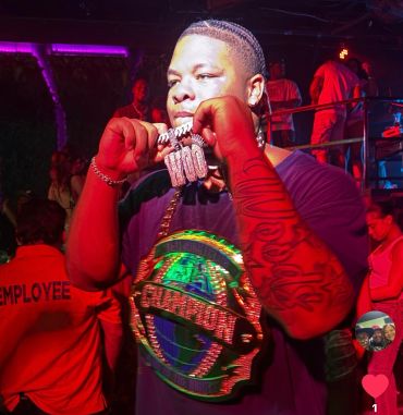 Man showing his iced-out chains in a nightclub.