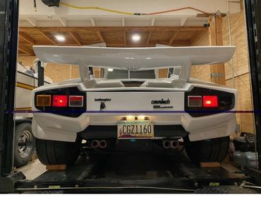 Rear view of a white Lamborghini Countach in a garage.