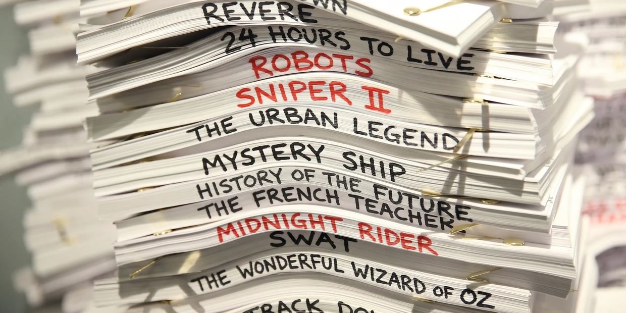 Stack of scripts for various films, some titles in red.
