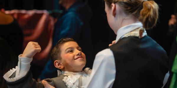 Boy showing muscles proudly to woman.