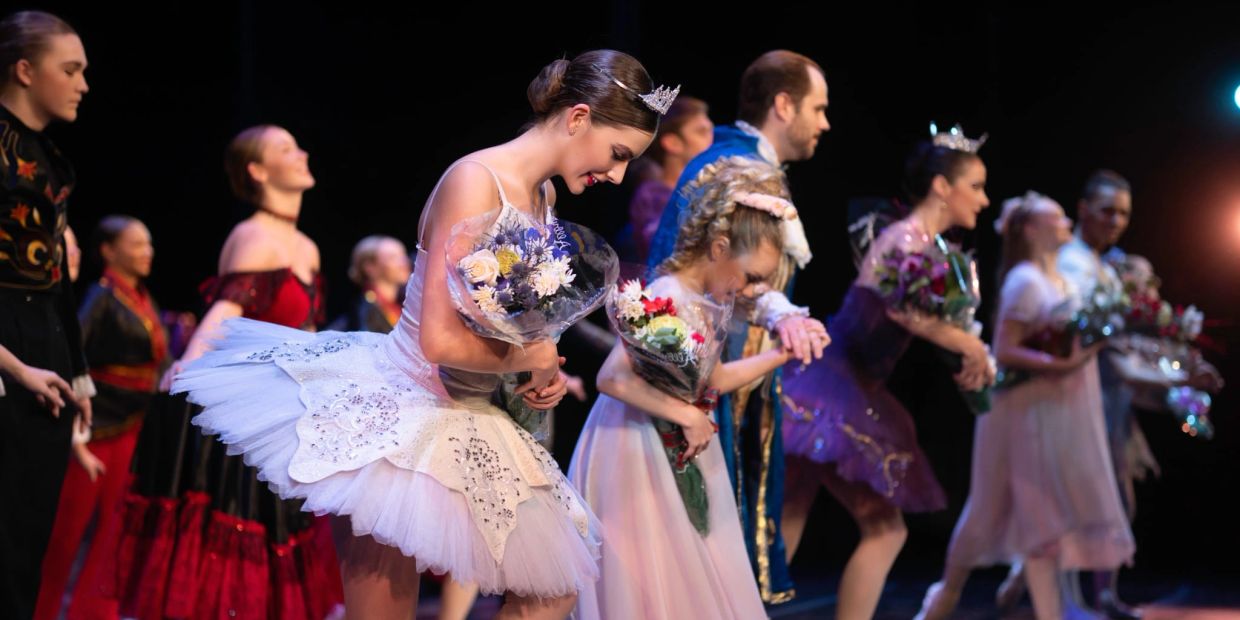 Ballet and theater performers bowing on stage with flowers.