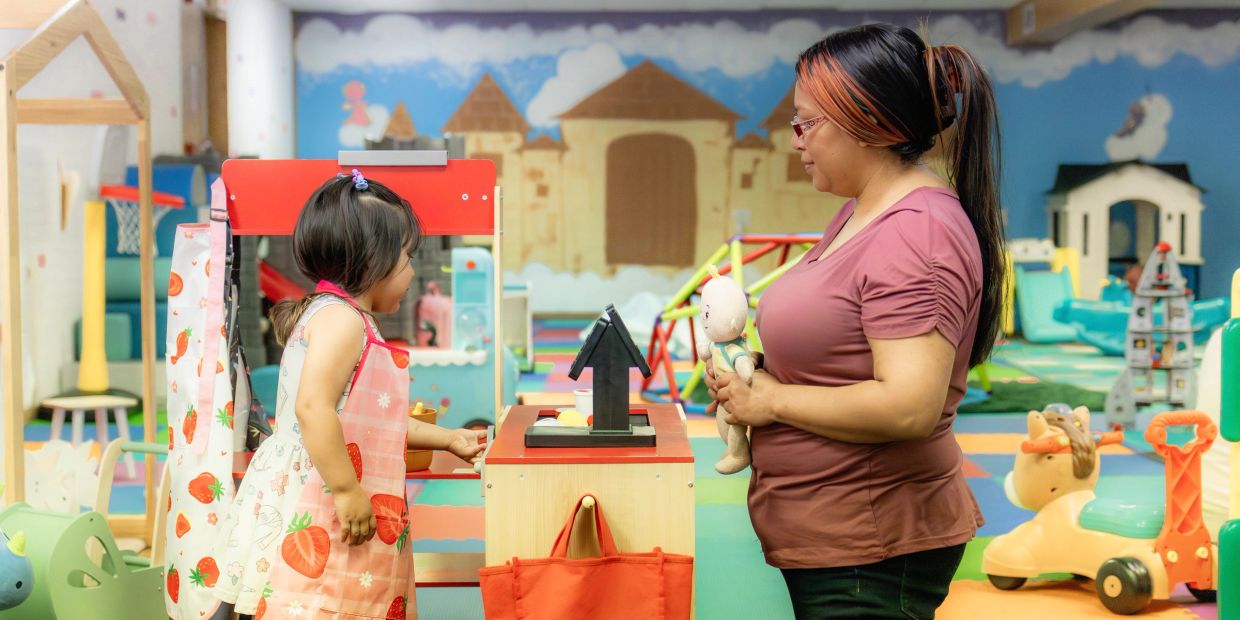 Child and adult playing in a colorful indoor playroom.