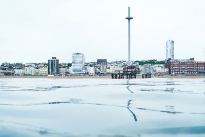 Calm waterfront cityscape with boats docked and a tall observation tower.