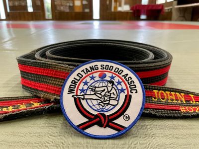 A Karate master's belt with the World Tang Soo Do Association patch laying in front of it.
