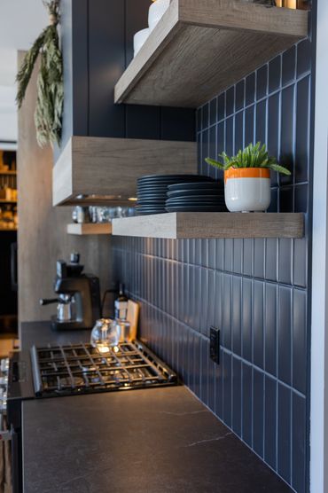 Floating oak kitchen shelves on black tile back splash
