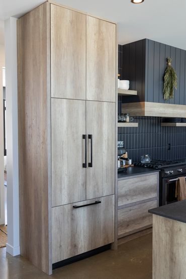 Built-in kitchen appliance cabinets with oak panels covering fridge