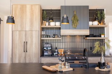 Oak kitchen with black tile backsplash and black wood panel stove fan