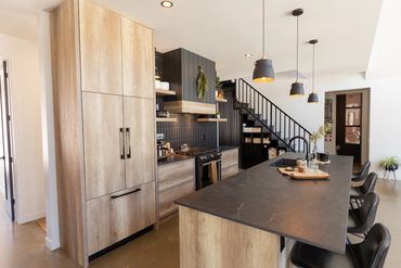 Full view of oak kitchen with black island and hanging black lights