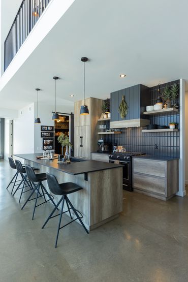 Side angle view of oak kitchen with black appliances and leather stools