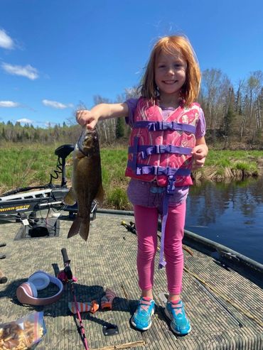 Child on a boat with a smallmouth bass
