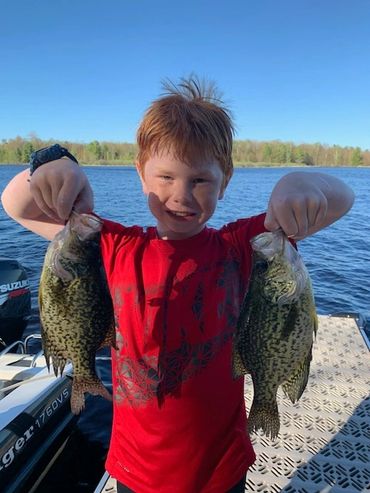 Child on the Johnson's Resort dock holding two crappie