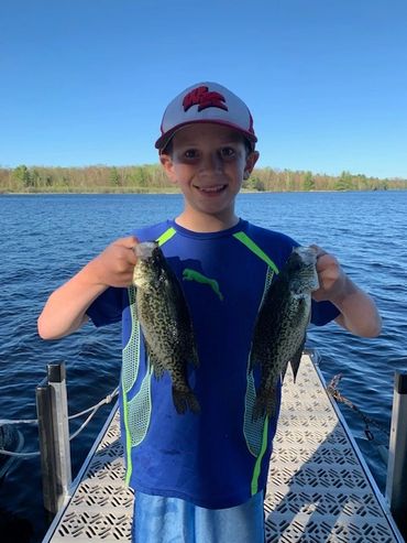 Child on the Johnson's Resort dock holding a two crappie