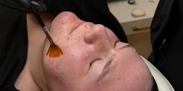 Person getting a facial treatment with a brush.