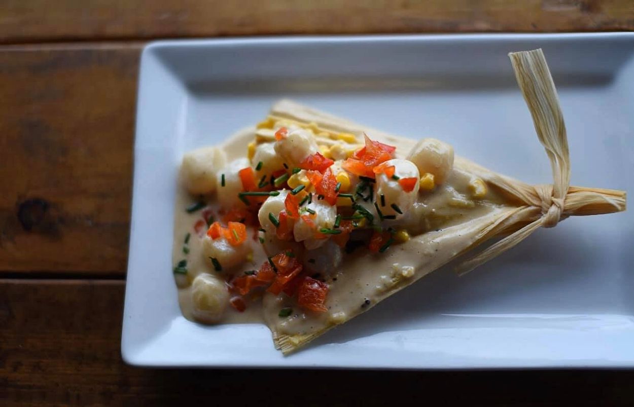 A colorful sunset over a calm lake with silhouettes of trees and mountains in the background.