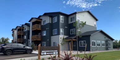 Freestone Apartments. Exterior image of a navy and grey apartment complex, with wooden balconies. 