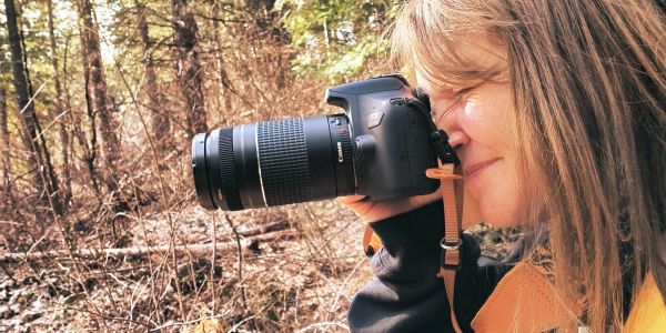 Woman photographing outdoors with a DSLR camera.