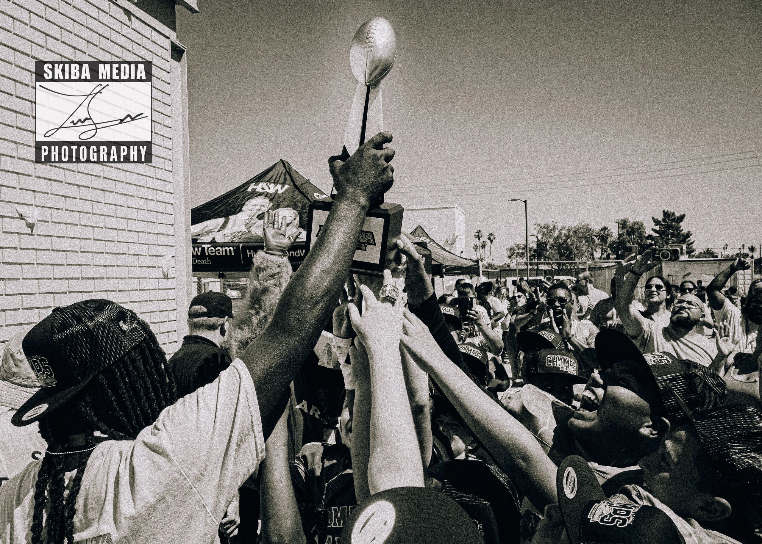 A diverse group celebrating with a football trophy in the air.
