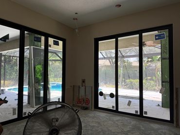 Room under construction with large glass sliding doors overlooking a pool area.
