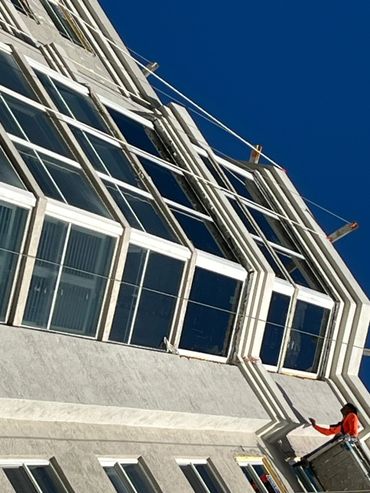 Worker on a lift repairing or inspecting windows on a tall building.