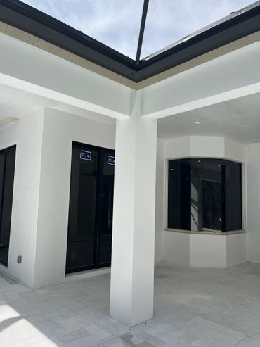 Modern white patio area with glass windows and a screened roof.