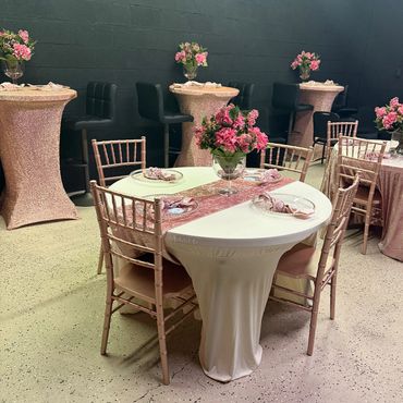 Elegant party setup with pink floral decorations and velvet table runners.