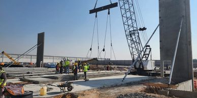 Obreros y maquinaria en construcción bajo cielo despejado.