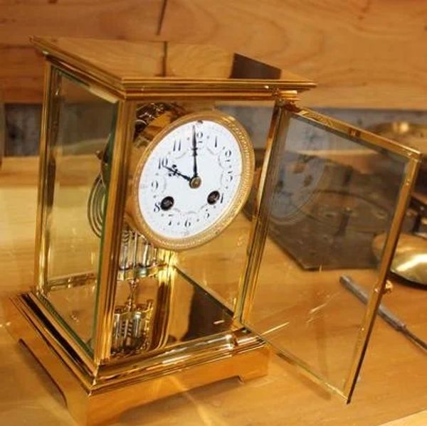 Antique glass and gold mantel clock with its door open.