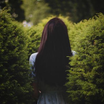 Woman with long hair in a green garden.