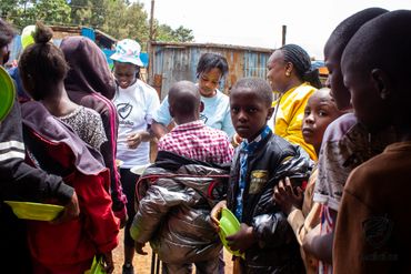 February 24th Action - children lined up with green bowls waiting to be filled
