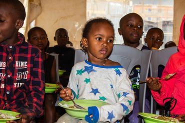 February 24th Action - young kids eating beans and rice from green bowls