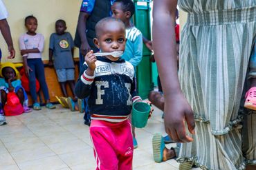 February 10th Action - Young child with a fork and cup of porridge in their hand