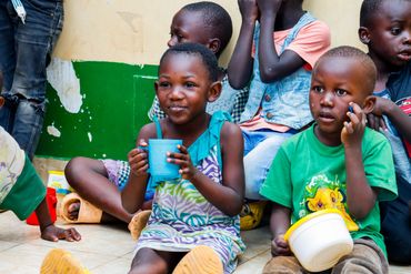 February 10th Action - young girl and boy with cups of porridge in their hands - little girl smiling