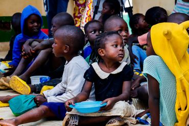 February 10th Action - Children sitting on the floor at event, young girl with empty bowl