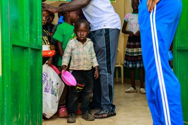 February 10th Action - Young boy with a pink bowl waiting in line for food to be served