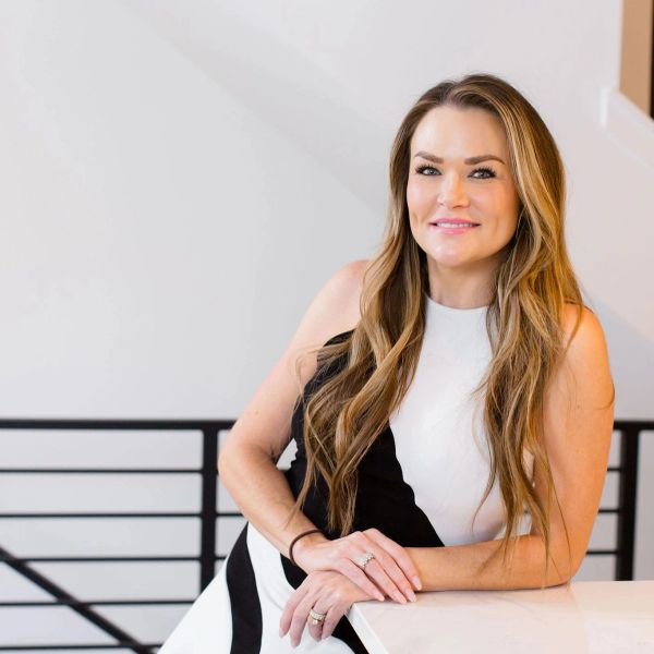 Smiling woman with long hair leaning on a table.