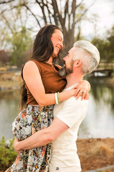 Couple joyfully embracing outdoors by a lake.