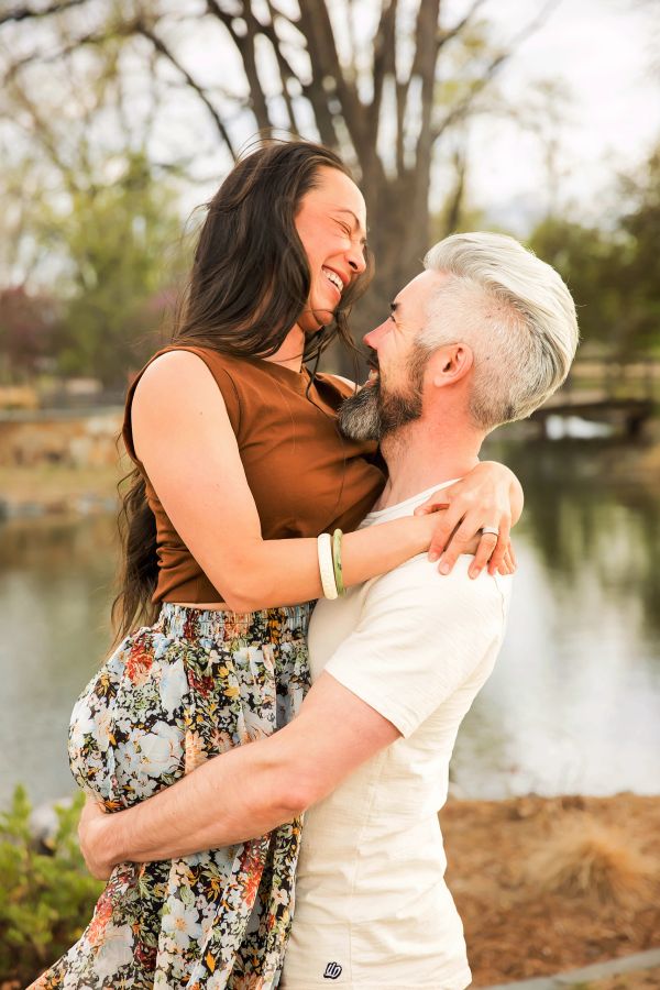 Couple joyfully embracing outdoors by a lake.