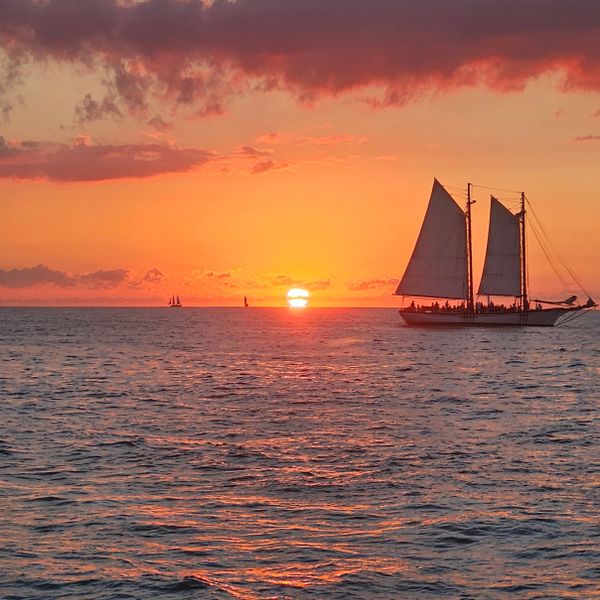 Sailboat gliding on the ocean during a vibrant sunset.