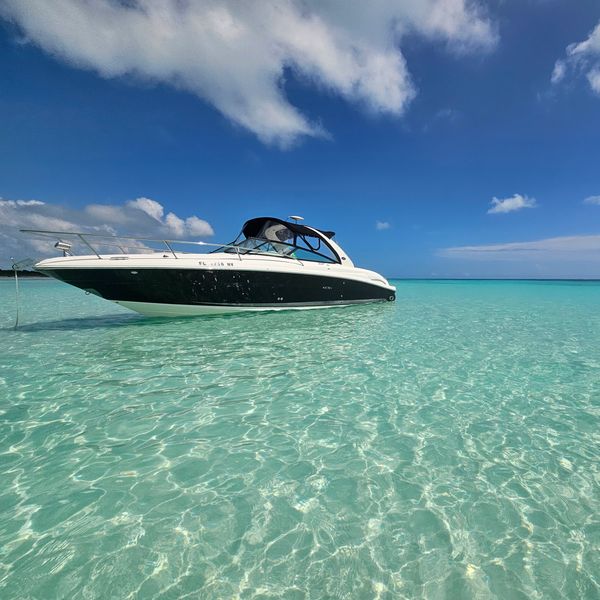 A sleek boat floating on crystal-clear turquoise waters under a bright blue sky.