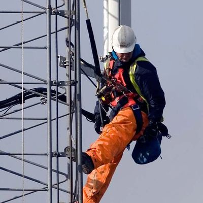 an electrician on the job with personal protective fall arrest equipment on a highrise with high viz