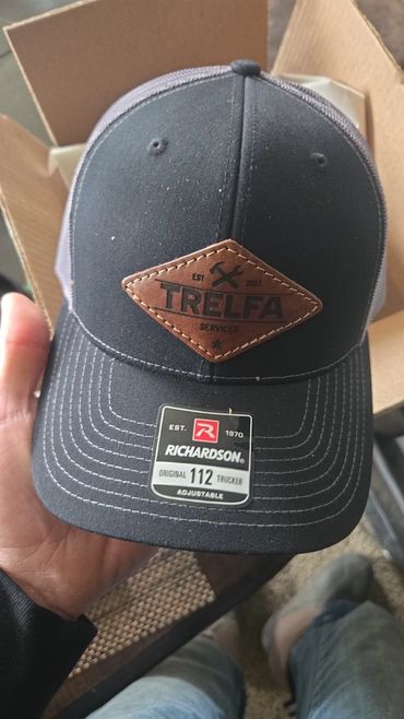 Black Richardson trucker hat with Trelfa Services leather patch.