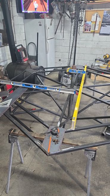 Metal frame structure under construction in a workshop with tools and equipment around.