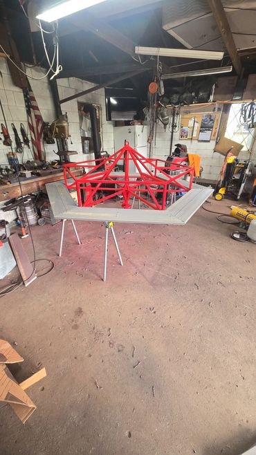 Red metal frame structure on a stand in a workshop.