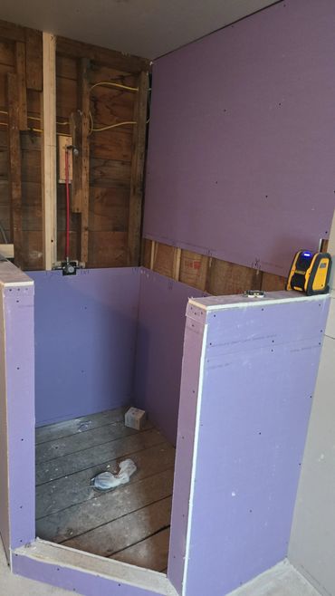 Partially constructed shower area with purple moisture-resistant drywall.