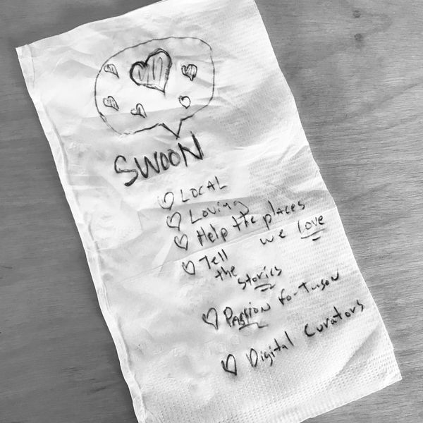 A to-go napkin with ideas and hearts scribbled on it in black ink including SWOON, Local, and Loving