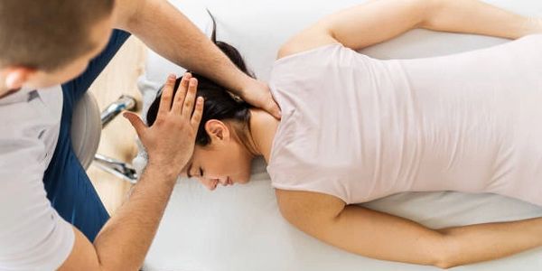 Chiropractor adjusting a woman's neck during a therapy session.