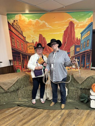 A family caregiver poses with their disabled adult child at a western themed community event. They a